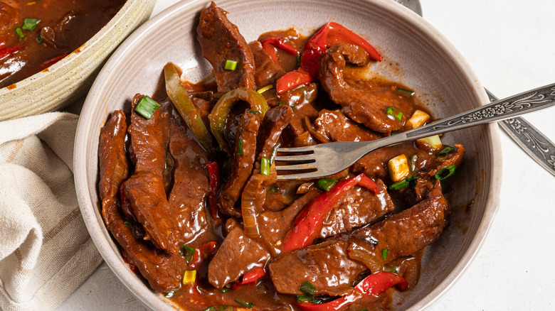 Plate with pepper steak in a brown sauce with a fork inside