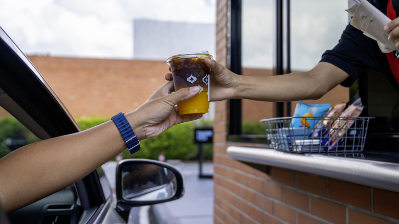 Server delivers drinks through window at drive thru service