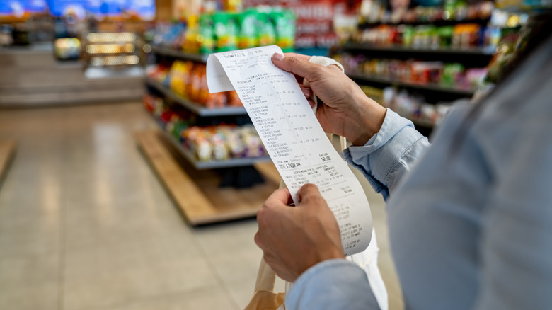 Woman looking at a grocery receipt in a store
