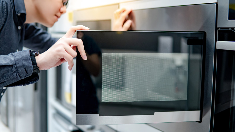 A shopper looks into the inside of a stainless steel microwave