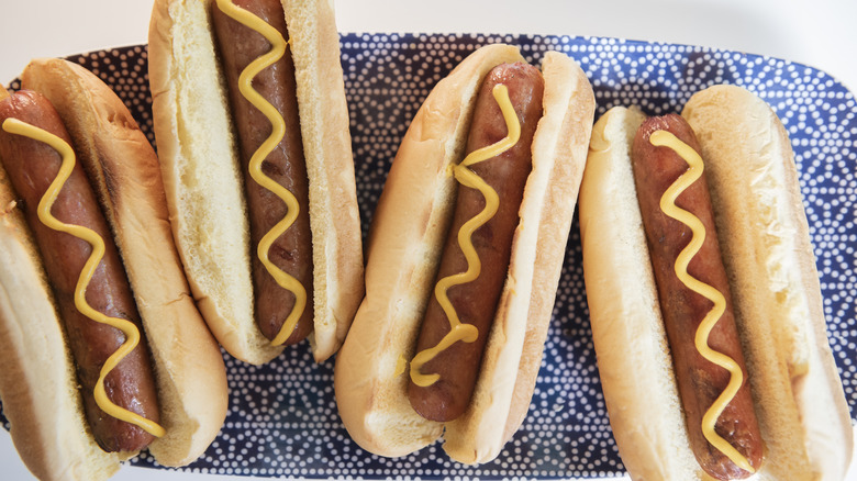 Four hotdogs resting on a blue plate