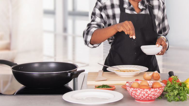 Woman in apron seasoning eggs with salt